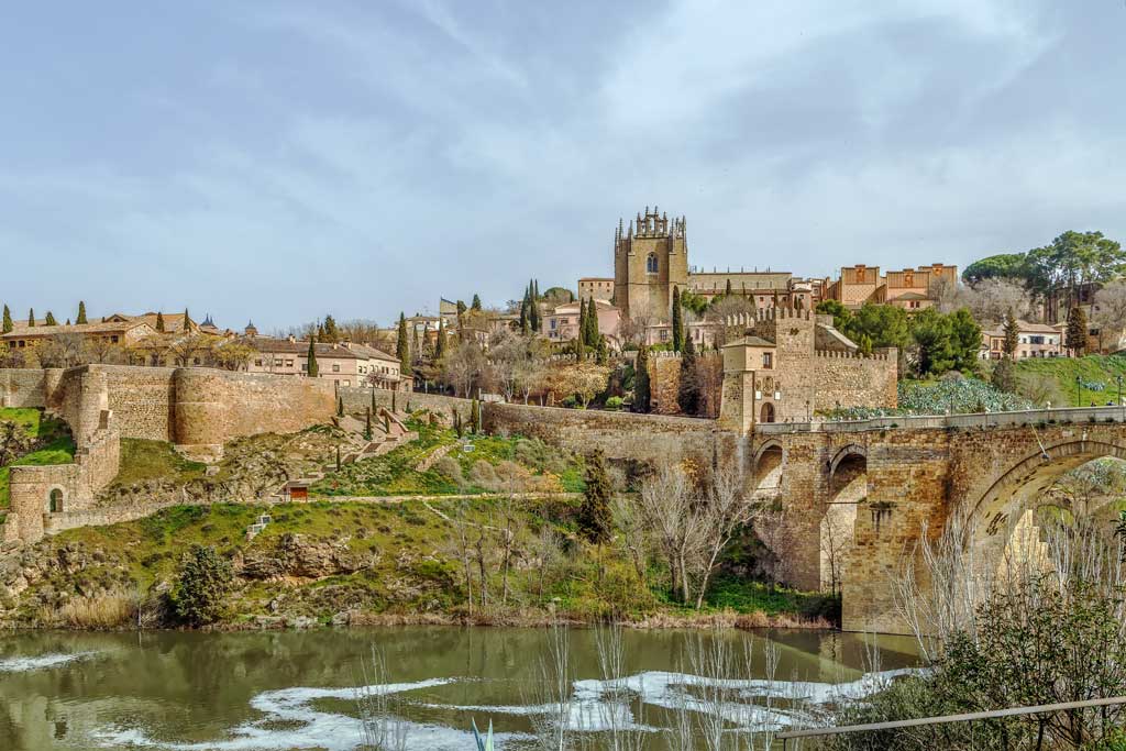 Spania. Toledo. Utsikt mot Toledo fra Tajo-elven. Brua San Martin og klosteret San Juan de los Reyes. Foto